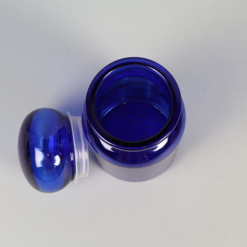 Öppen blå apoteksburk med lock bredvid