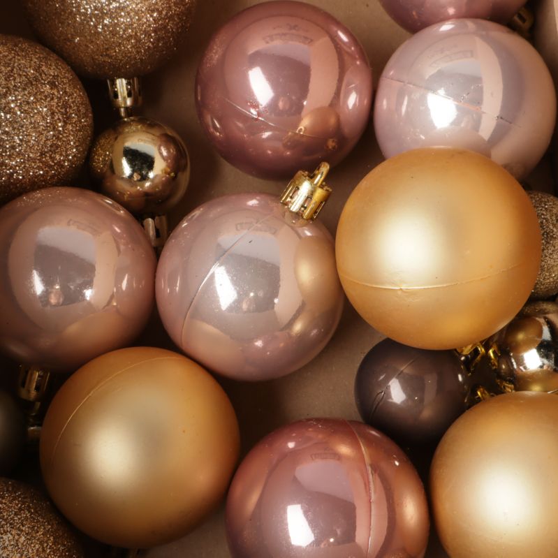 Närbild på blanka och glittriga julkulor i pastell och guld
