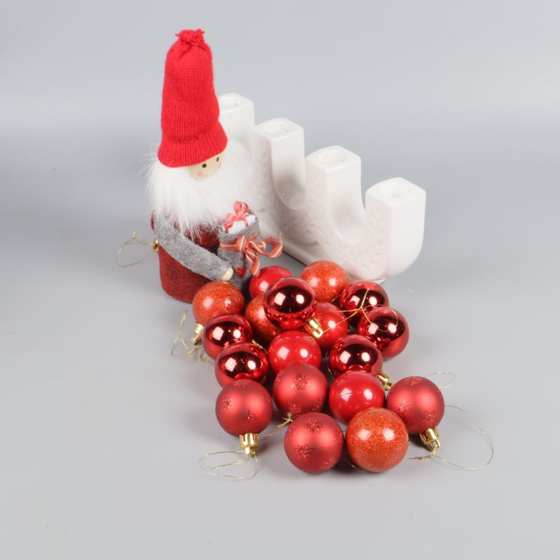 Röda julkulor framför tomte och adventsljusstake