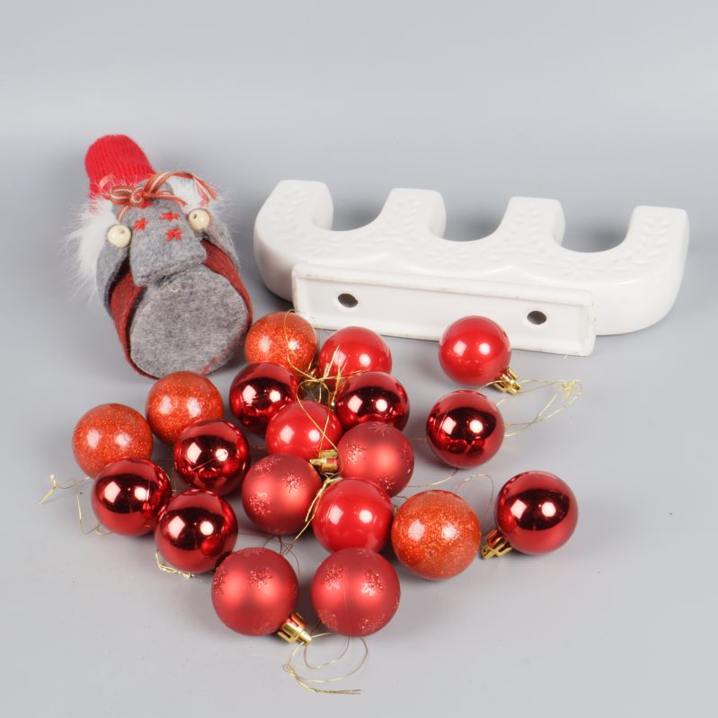 Adventsljusstake och tomte liggande bland röda kulor