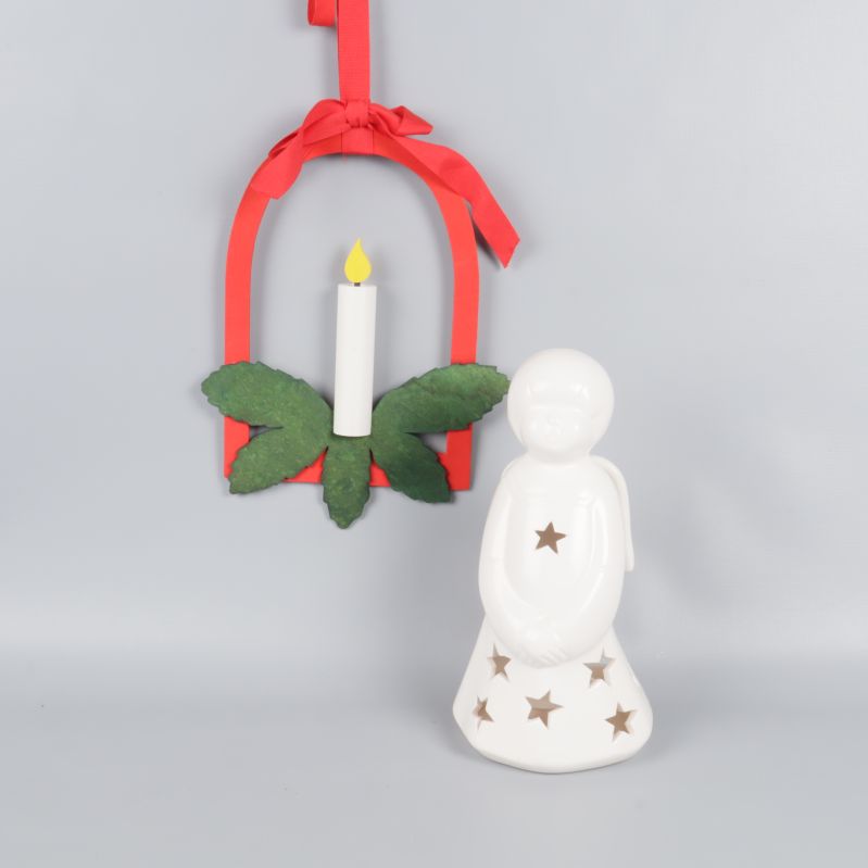 Vit ängellykta med stjärnor och röd hängprydnad med konstljus