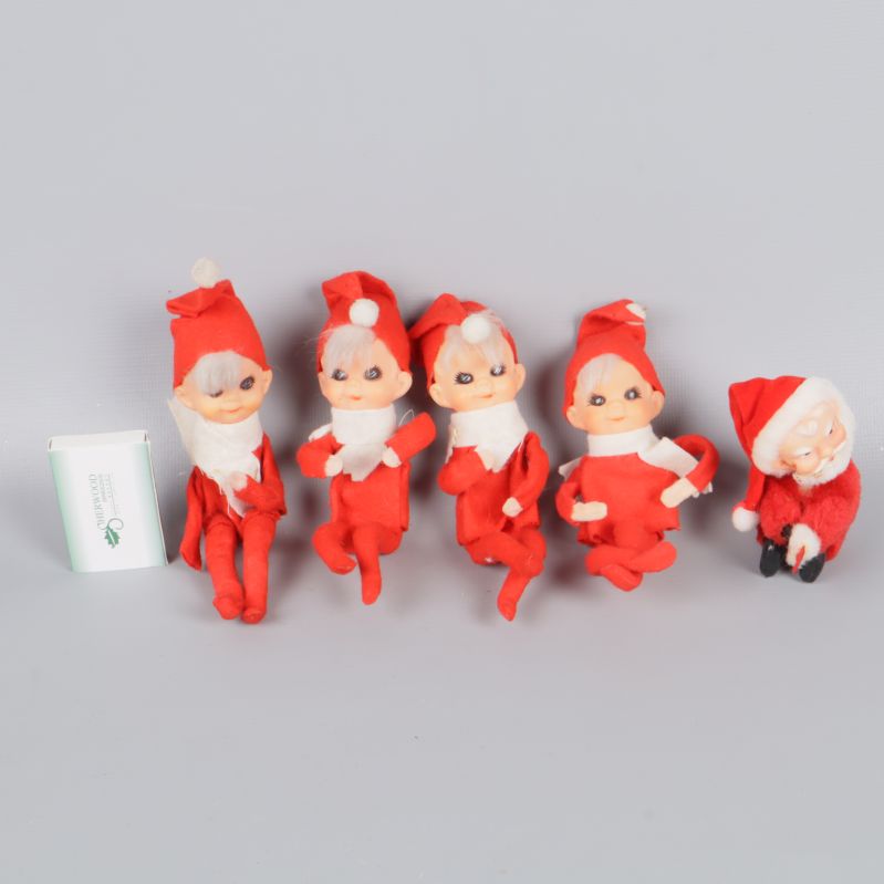 Fyra små tomtar och en till i röda kläder