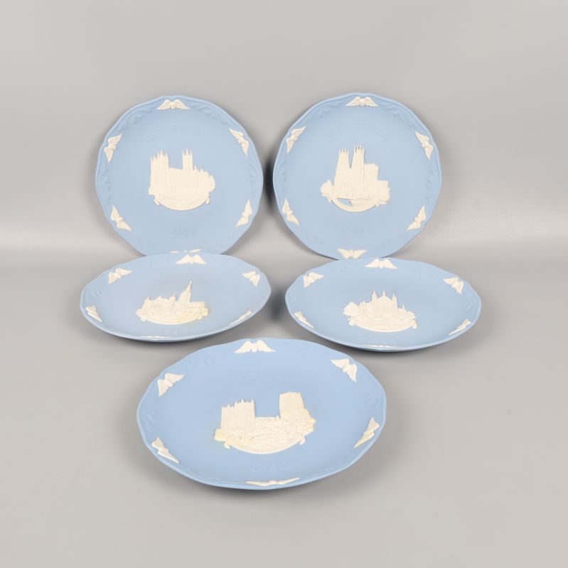 Fem blå tallrikar med vita reliefer och motiv