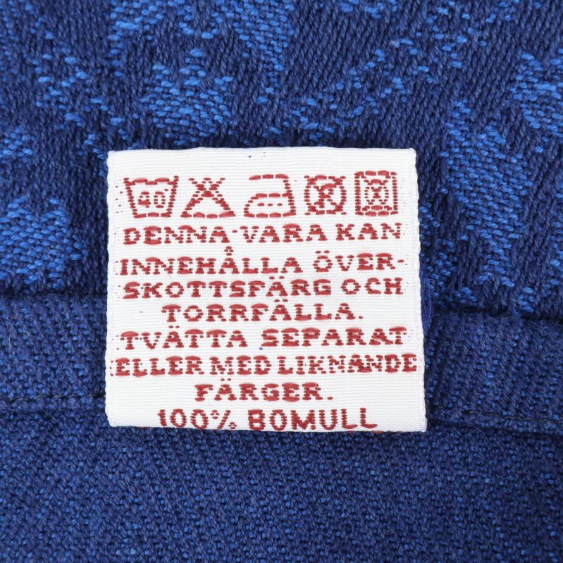 Tvättrådsetikett med information om 100% bomull och tvättråd