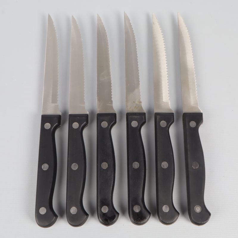 Sex köttknivar med svarta handtag och tandade blad