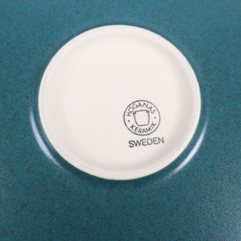 Närbild på Höganäs Keramik-stämpel och botten av tallrik