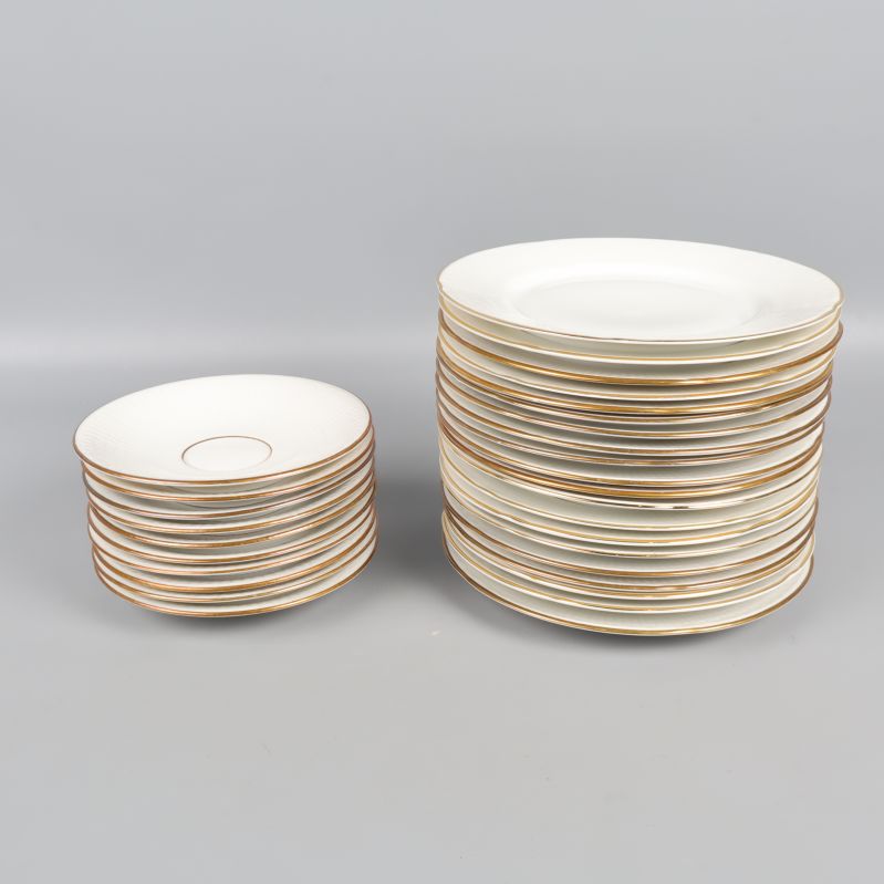 Staplade fat och assietter i vitt porslin med guldkant