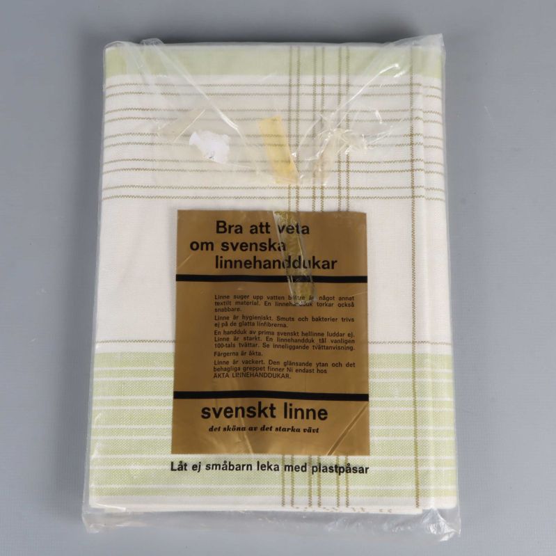 Handduk i halvlinne med grönvitt rutmönster och informativ etikett om svenskt linne