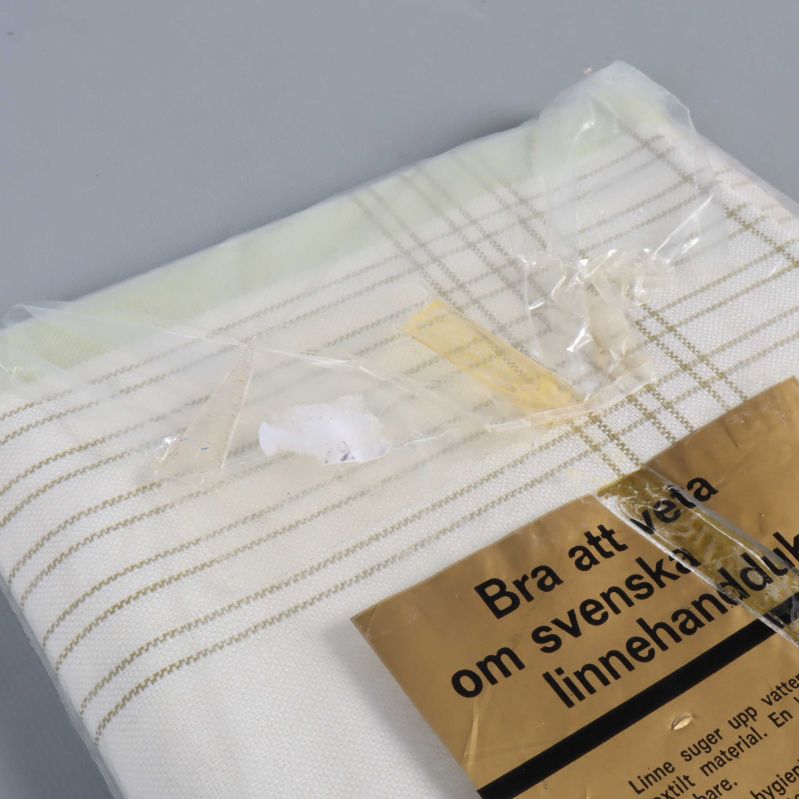 Handduk i halvlinne med rutmönster och plastförpackning i närbild