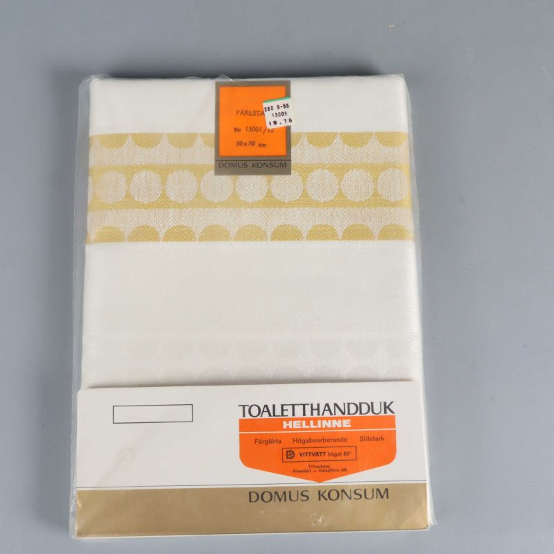 Vit toaletthandduk i förpackning med guldfärgat pärlmönster