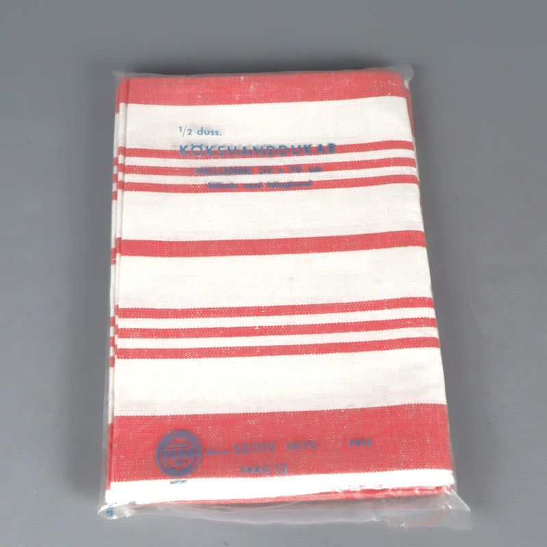 Rödvit randig kökshandduk i förpackning mot grå bakgrund