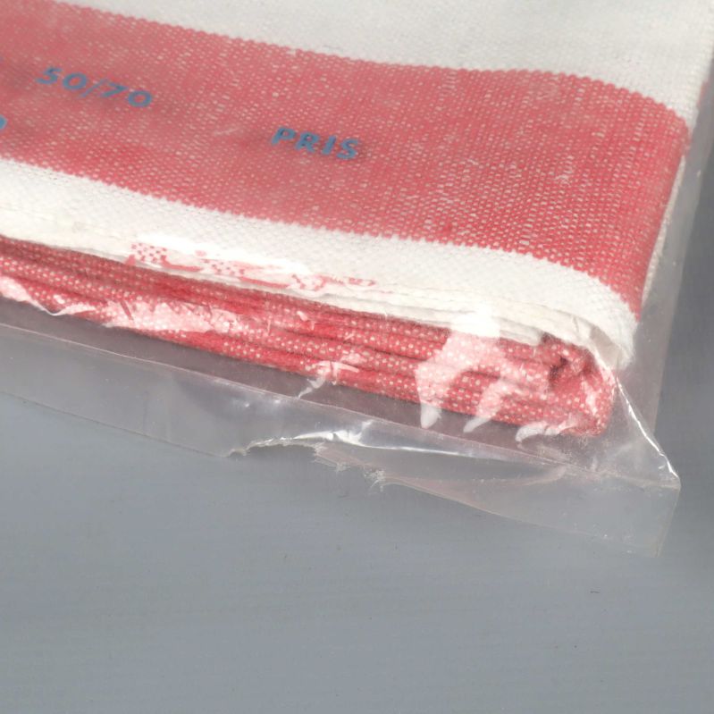 Närbild på hörn av kökshandduk i plast, röd och vit kant