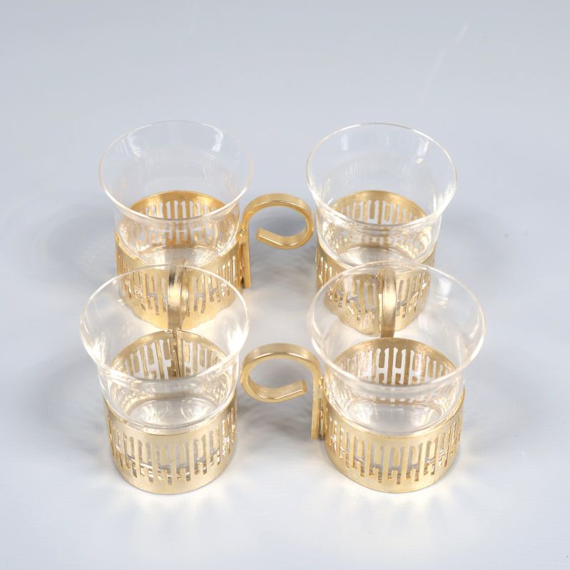 Fyra glaskoppar med guldfärgade hållare arrangerade i fyrkant