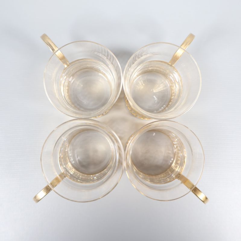 Vy ovanifrån av fyra glaskoppar med guldfärgad metall