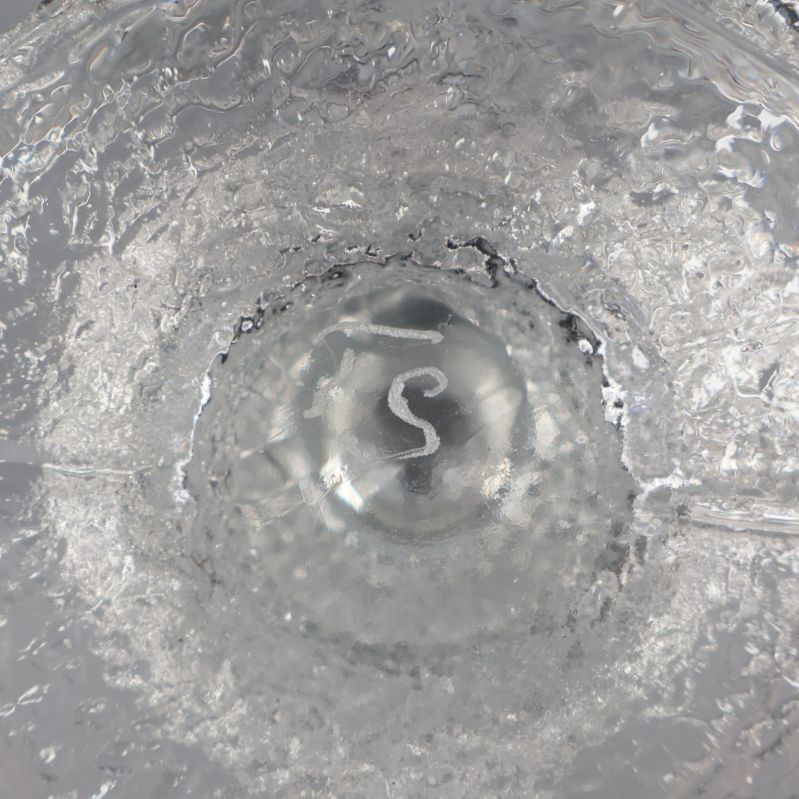 Signerad botten av glasljusstake i närbild