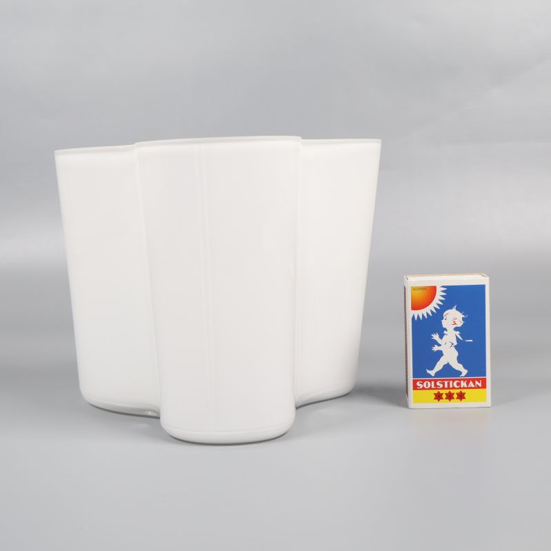 Vit vas bredvid tändsticksask för storleksjämförelse