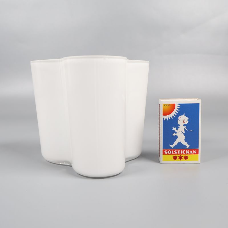 Vit vas bredvid tändsticksask för storleksjämförelse