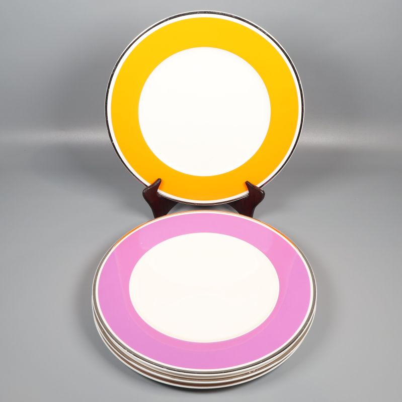 Fyra mattallrikar med orange och lila kant på ställ