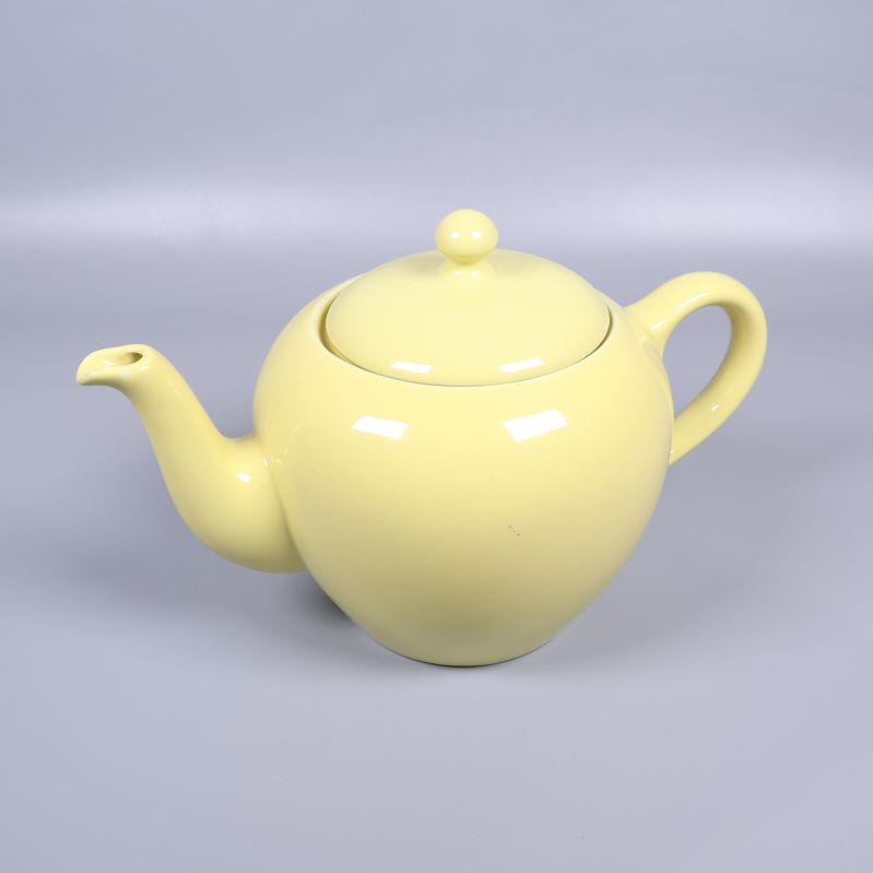 Gul tekanna med lock fotograferad från sidan