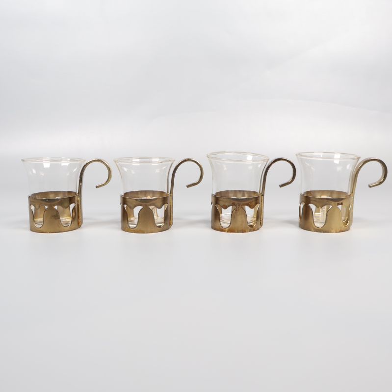 Fyra glasmuggar med mässingsfärgat handtag i rad