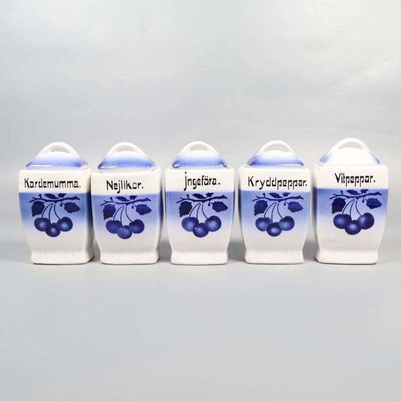 Fem blåvita kryddburkar med olika örtetiketter