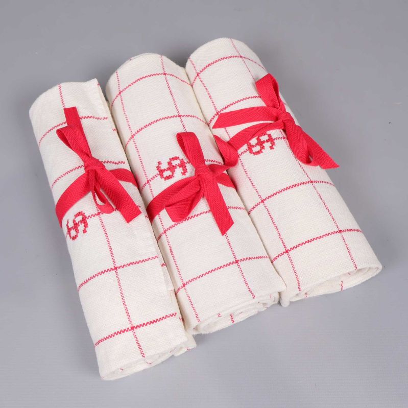 Tre hoprullade handdukar med röda band 