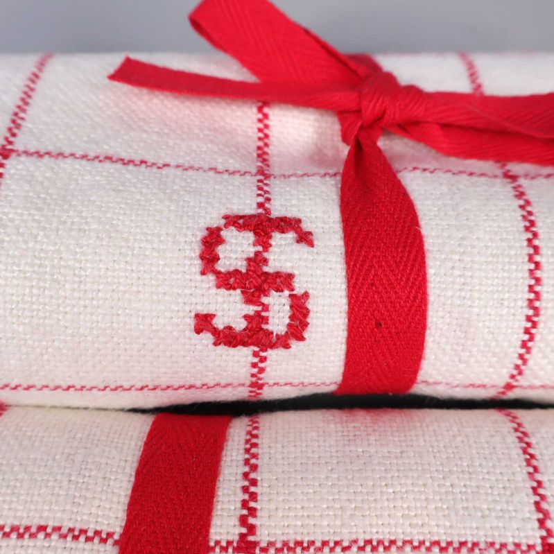 Närbild på rött band och broderad bokstav på handduk