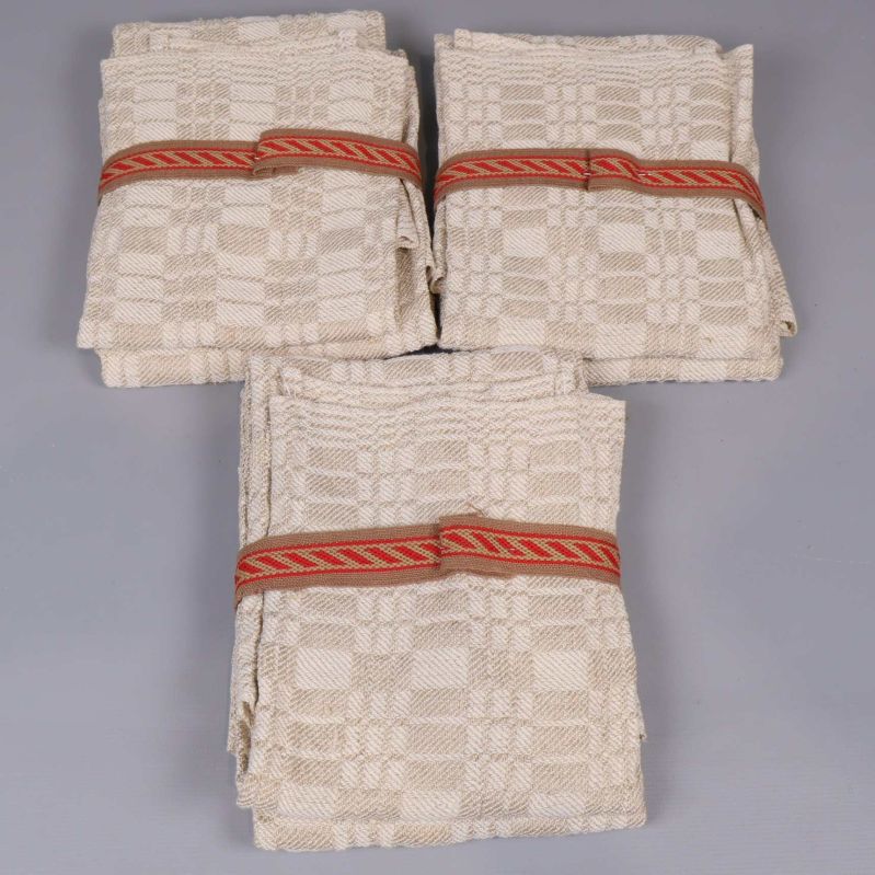 Uppifrån på tre vikta linnéhanddukar med bård