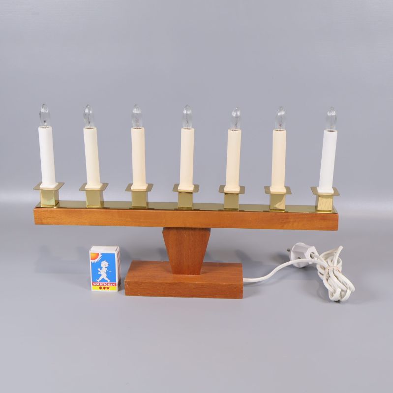 Adventsljusstake i trä och mässing bredvid tändsticksask