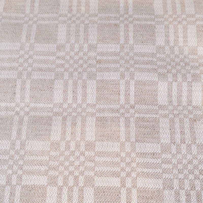 Närbild på tyg med beigefärgat invävt rutmönster
