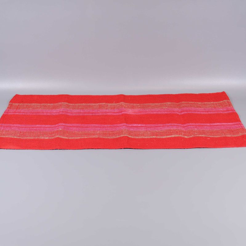 Röd löpare med dekorativa ränder utlagd på grå bakgrund