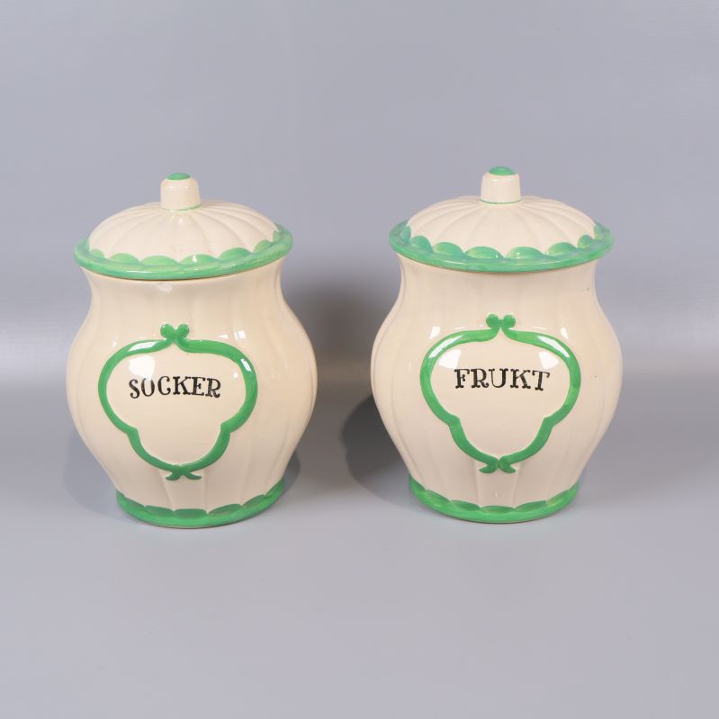 Två gräddvita burkar med grön kant och texten socker frukt