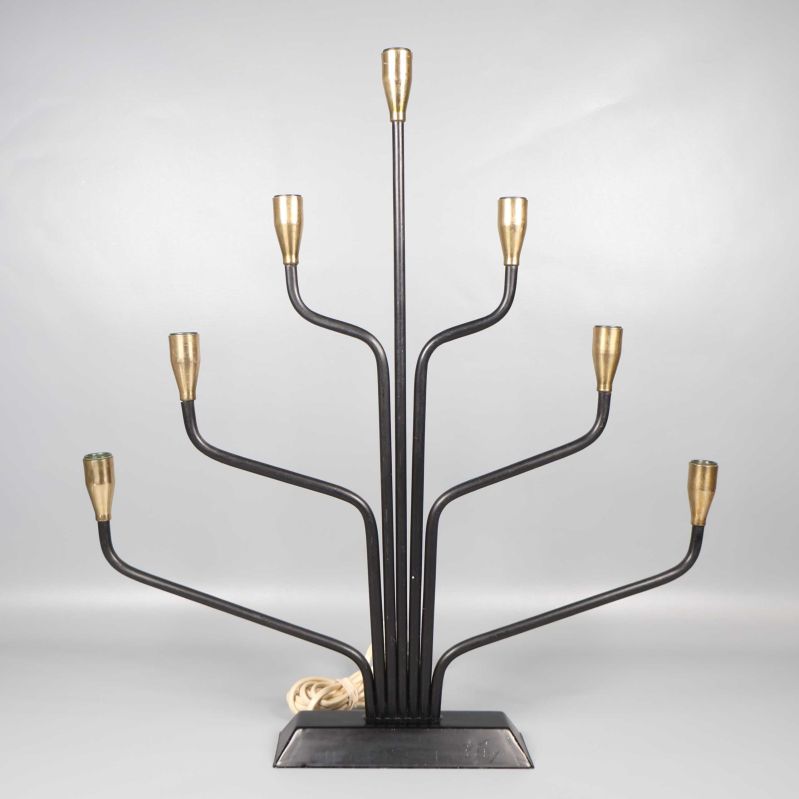 Sjuarmad svart ljusstake med mässingsdetaljer mot grå bakgrund