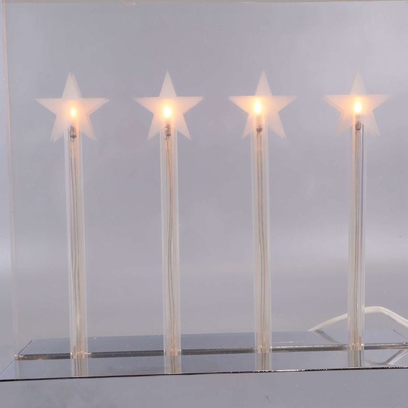 Närbild på fyra lysande stjärnor i adventsljusstake