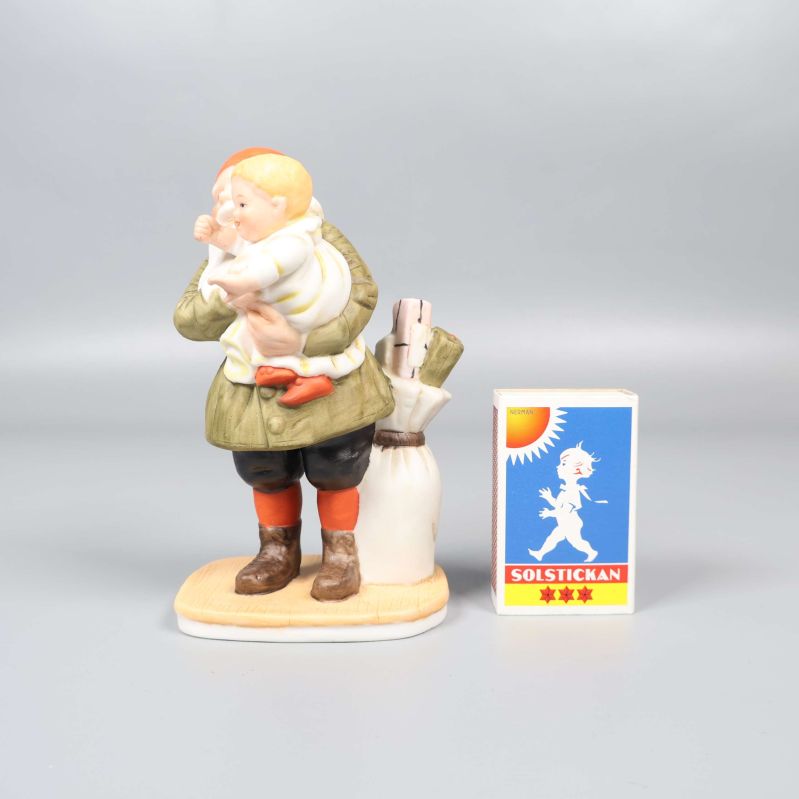 Porslinsfigur bredvid tändsticksask för storleksjämförelse