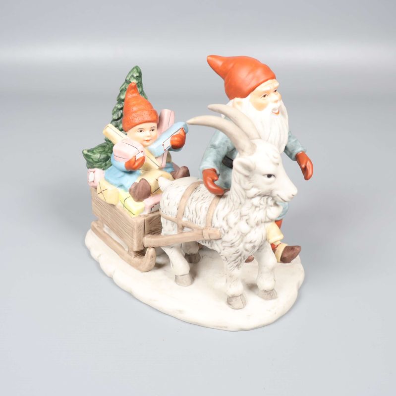 Tomtefigur med bock och släde på vit yta