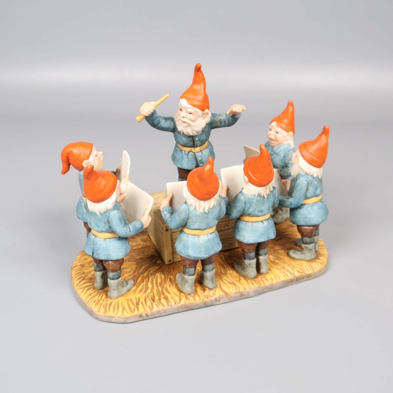 Tomtekör med dirigent i blå kläder och röda luvor