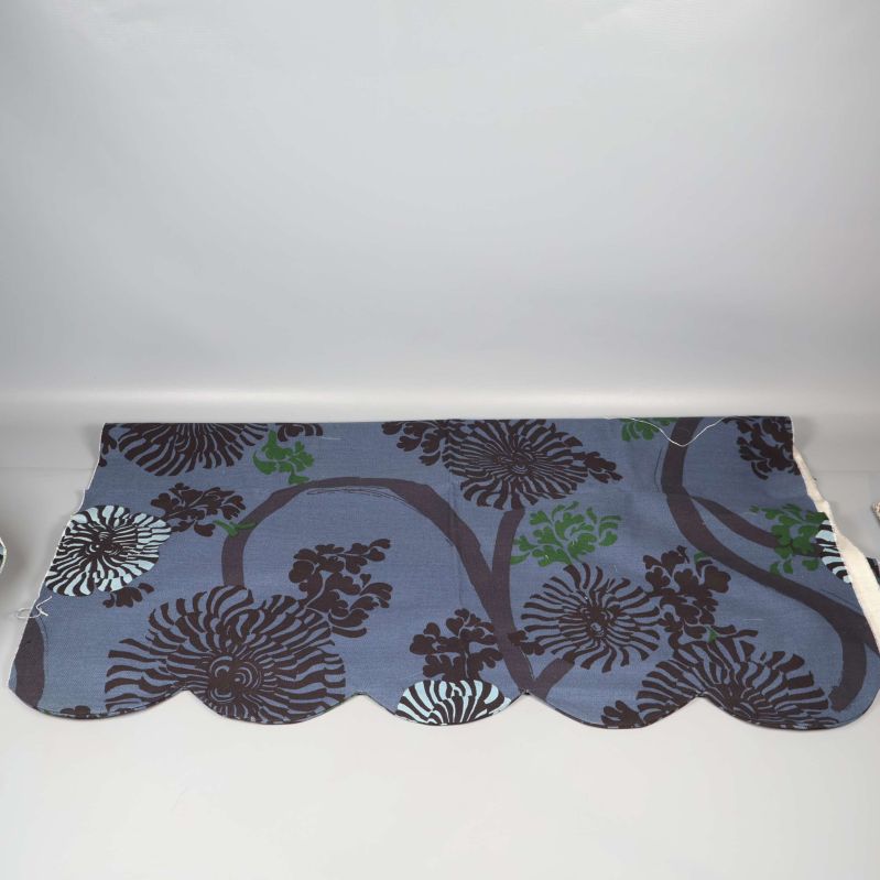 Gardinkappa med bladmönster och vågformad kant mot vit bakgrund