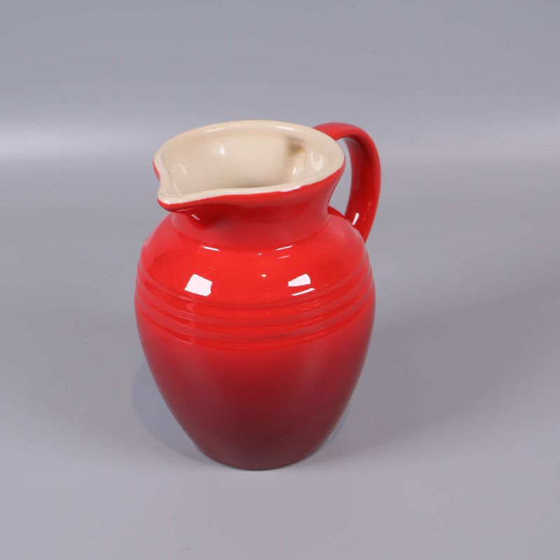 Röd liten kanna med handtag och ljus insida