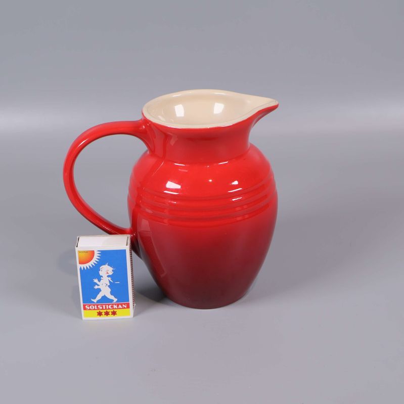 Röd kanna bredvid tändsticksask som storleksjämförelse