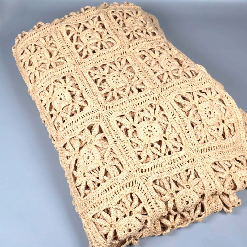 Vikt beige virkat överkast i närbild med rutmönster