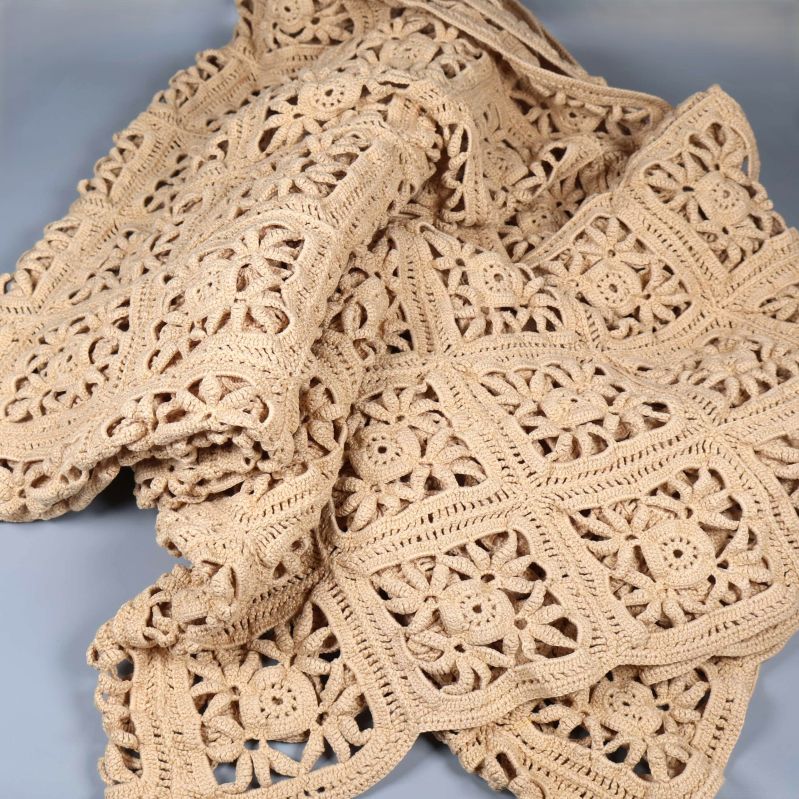 Utbrett beige överkast med dekorativa virkade detaljer