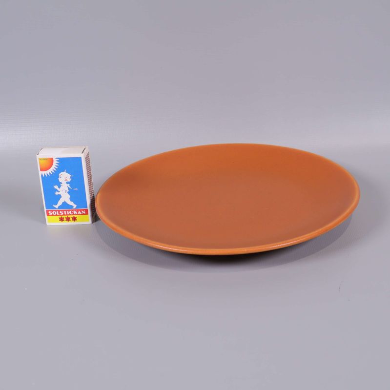 Orange keramikassiett bredvid en tändsticksask för storleksjämförelse