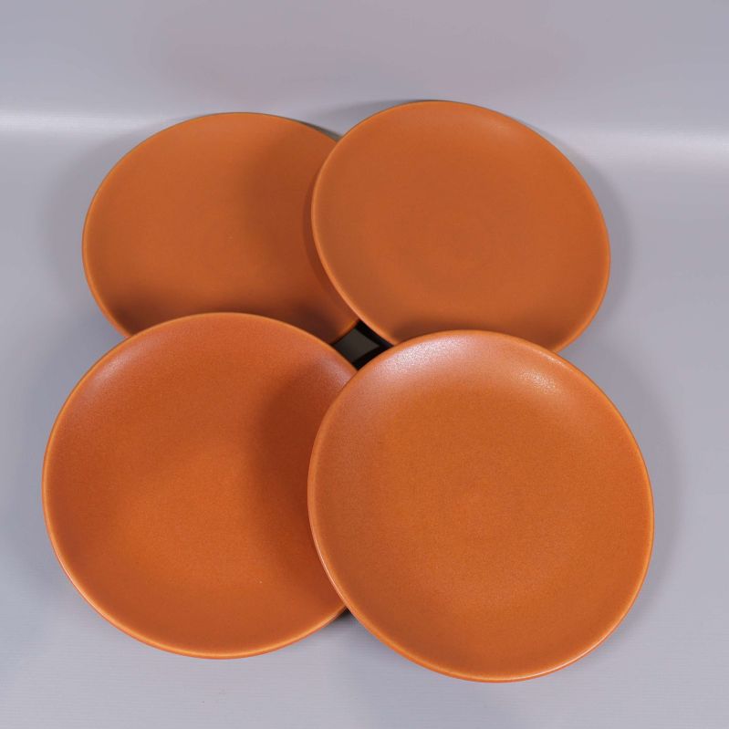 Översiktsvy på fyra orangea assietter mot grå bakgrund