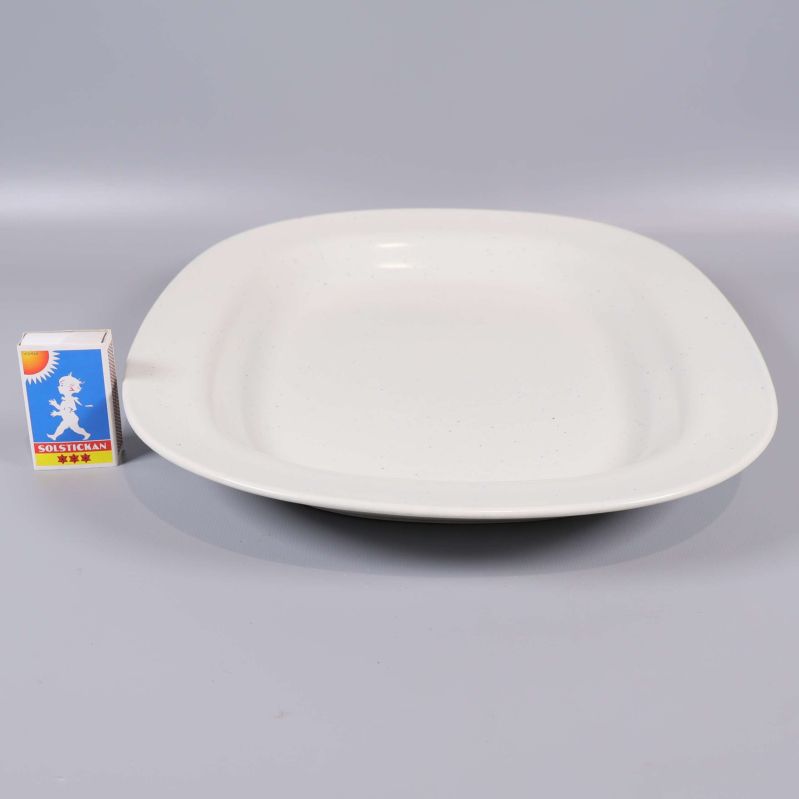 Vitt serveringsfat bredvid tändsticksask för storleksjämförelse