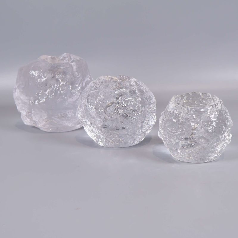 Tre glasljuslyktor uppställda på rad mot ljus bakgrund