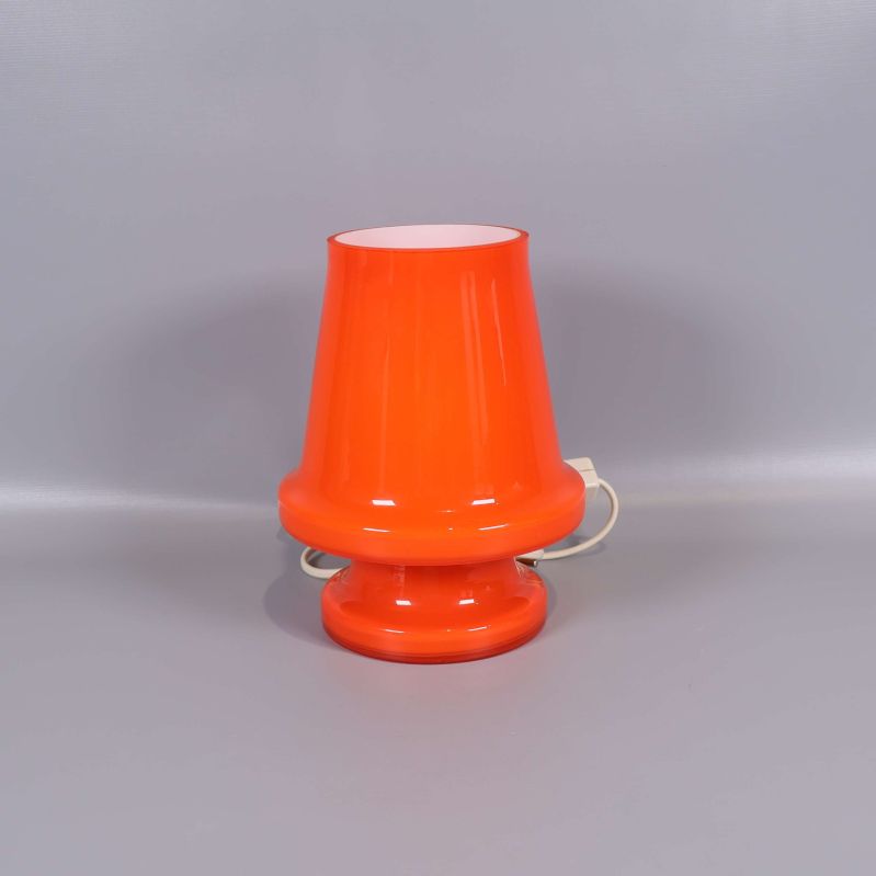 Orange bordslampa med konformad skärm mot ljus bakgrund