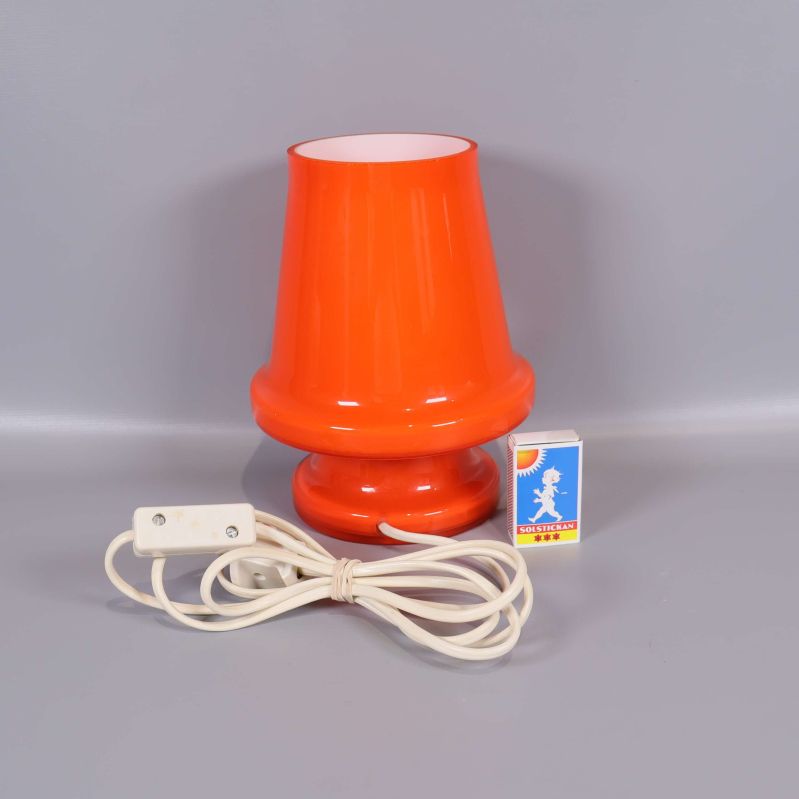 Orange bordslampa med vit sladd och tändsticksask för storleksjämförelse