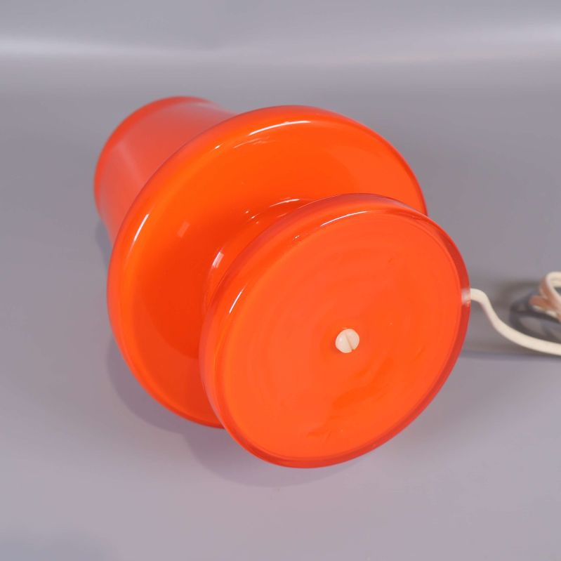 Orange bordslampa liggande med tydlig fot
