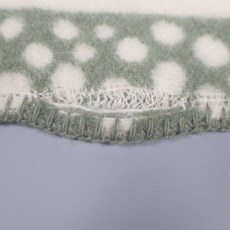 Närbild på filtens sydda kant i grönt och vitt